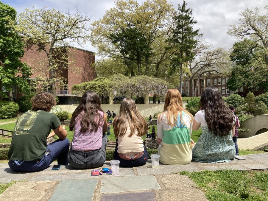 Five students watch a chorus performance in the amphitheater. 
